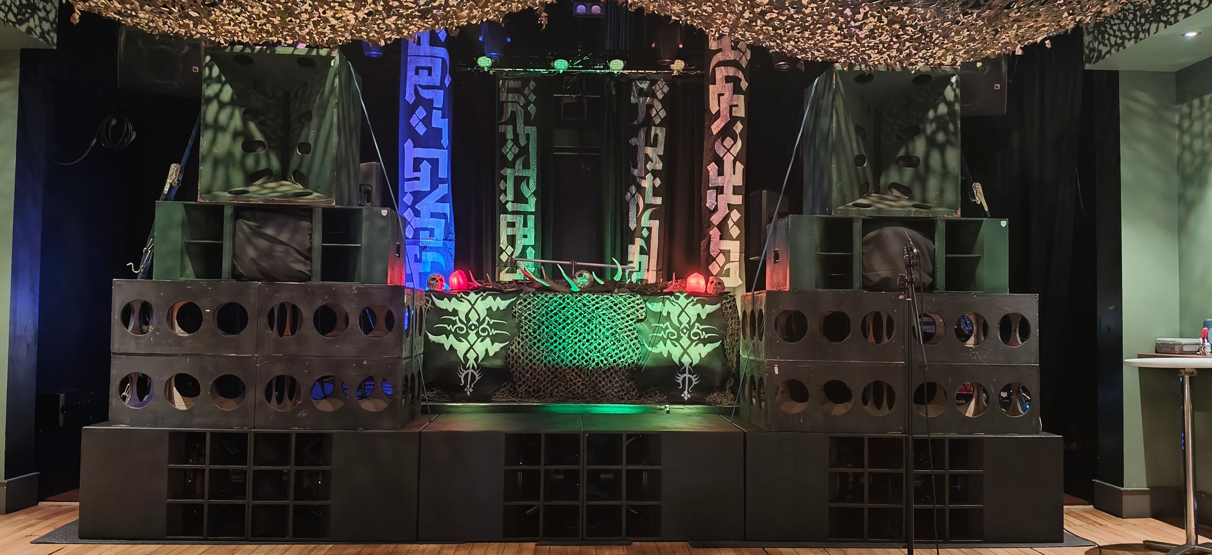 The stacks are in front of a well-lit stage, with blue, green and red light washing over banners of a strange alien script