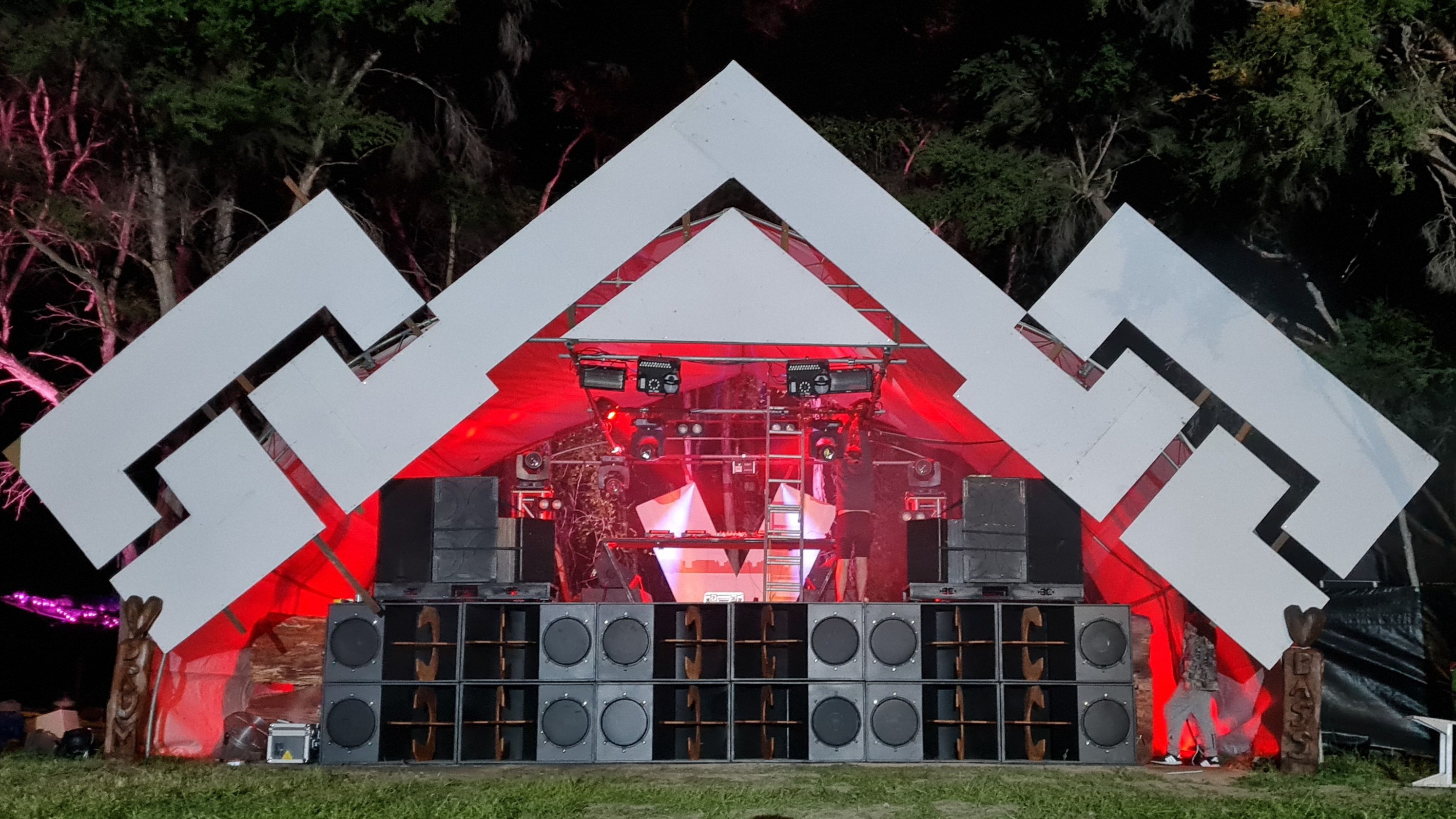 The rig at an outdoor stage, under a peaked stagefront. The stage inside is lit up with red lighting.