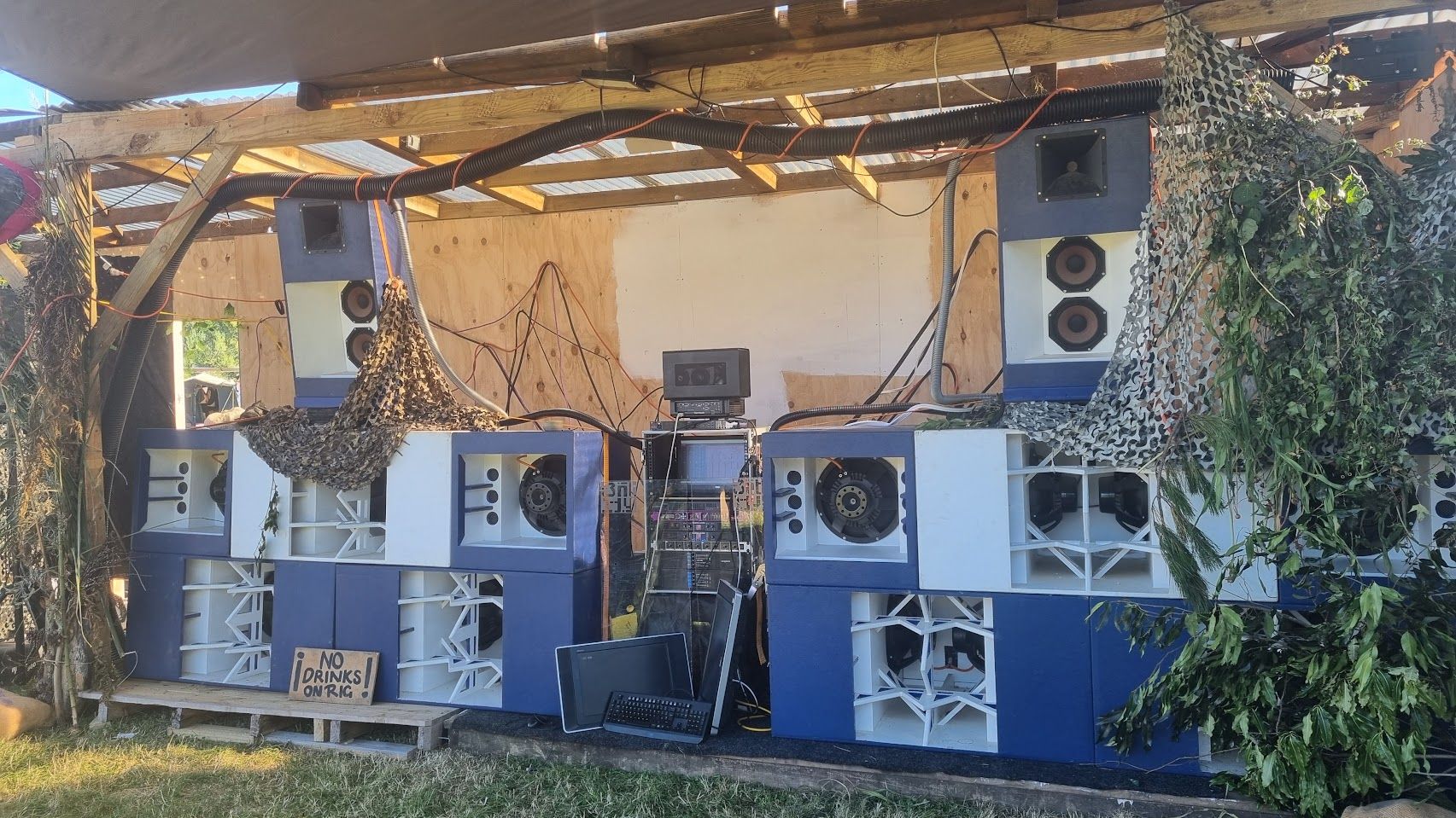 A huge array of speakers, painted blue and white, arranged in front of a wooden stage