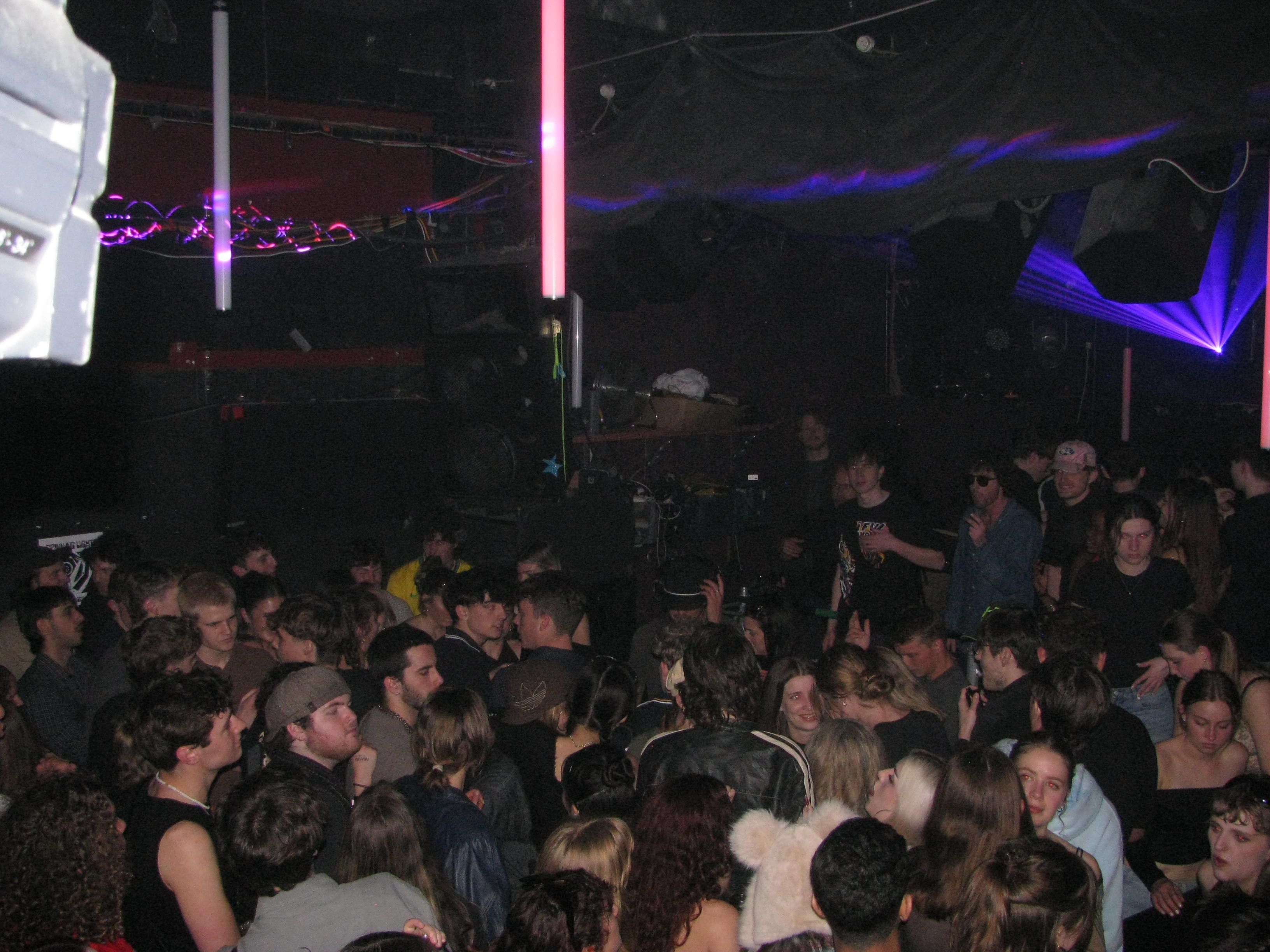 A crowd in a dark room, smiling and dancing. Lasers cut across the ceiling.