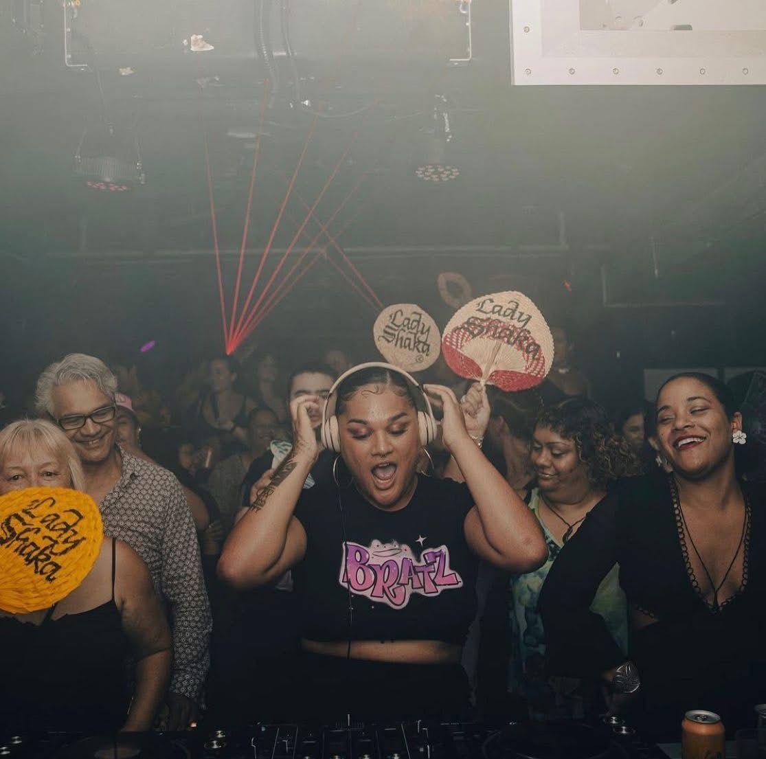 a dancefloor, many folks holding 'lada shaka' fans