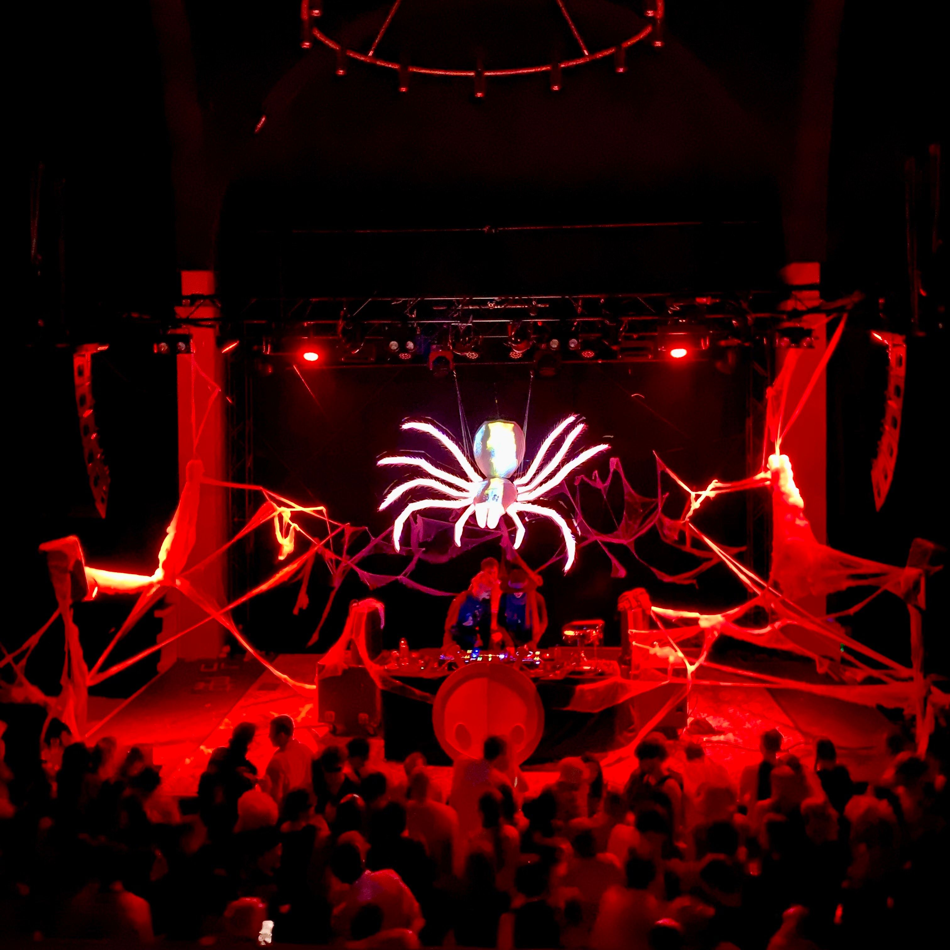 a giant spider lit up above a stage dressed as a giant web